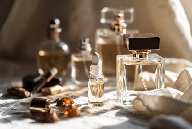 Perfume bottles and perfume oil arranged with oud wood amber resin and warm premium details for a Soghaat guide on making fragrance last longer