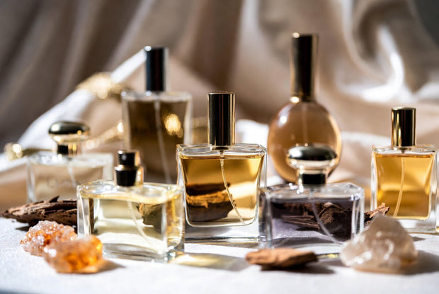 New fragrance arrival perfume bottles arranged with oud wood amber resin and warm premium details for a Soghaat discovery guide
