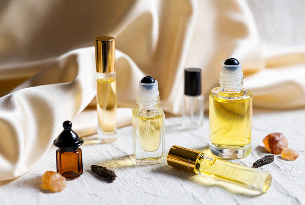Perfume oils and attar bottles arranged with oud wood amber resin and warm premium details for a Soghaat fragrance guide