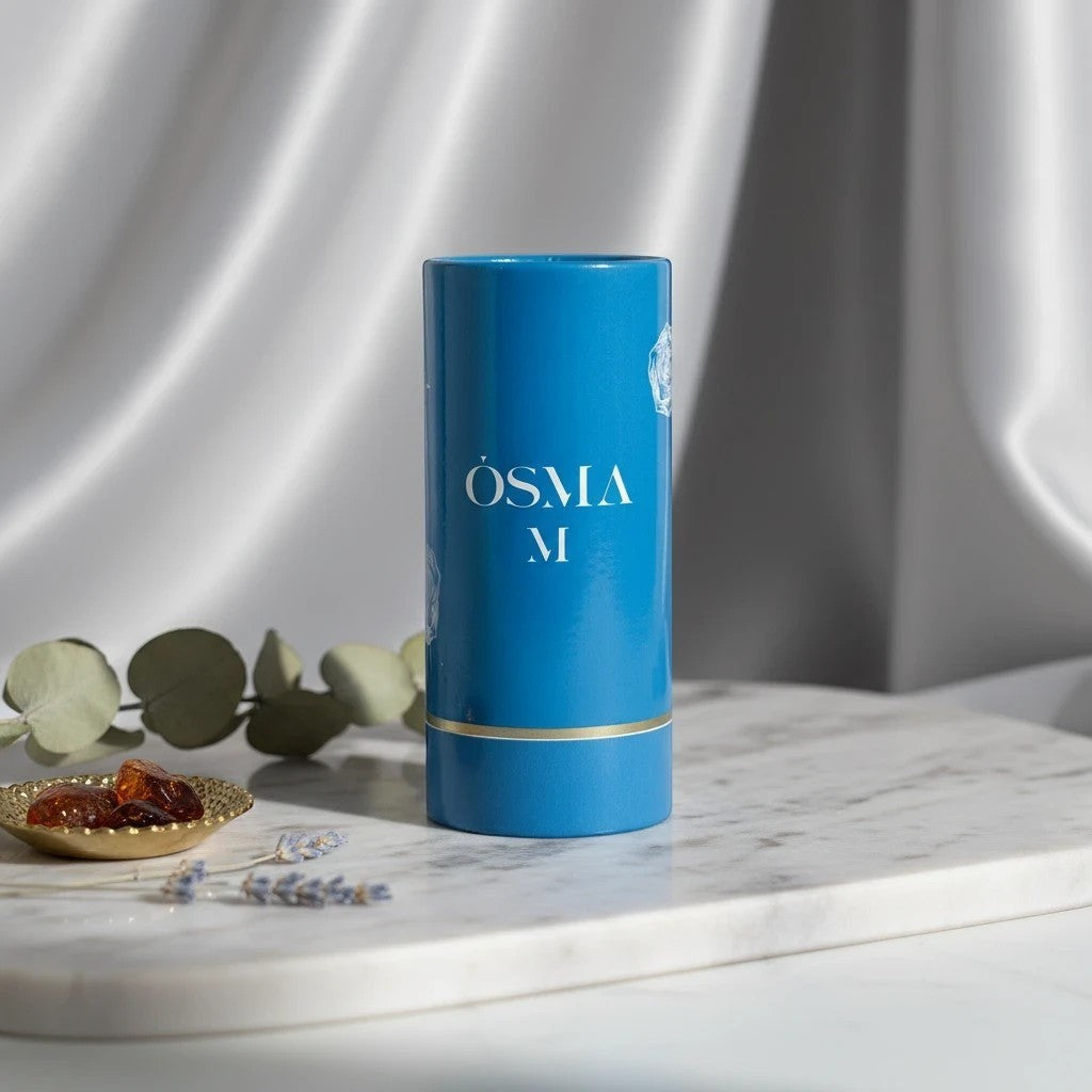 Osma M Eau de Parfum by Osma, a sweet gourmand fragrance in a blue cylindrical bottle with gold accents.