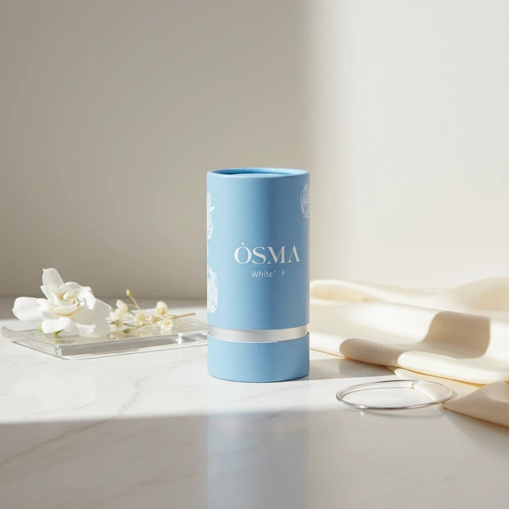 Osma White F Eau de Parfum by Osma, a sweet gourmand fragrance in a light blue cylindrical bottle with silver accents.