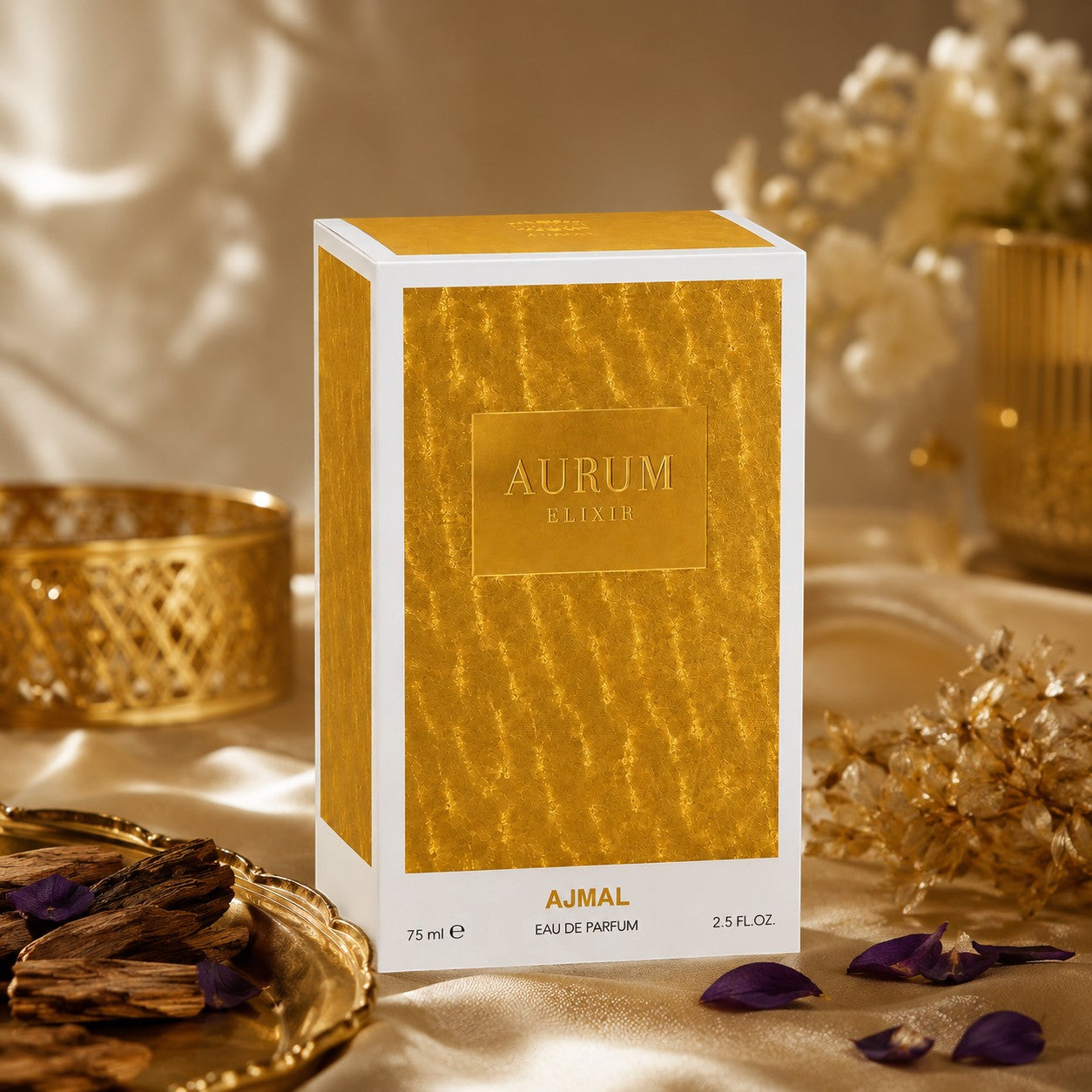 Soghaat Ajmal Aurum Elixir 75ml Eau de Parfum box in gold and white, displayed with wood chips and purple petals.