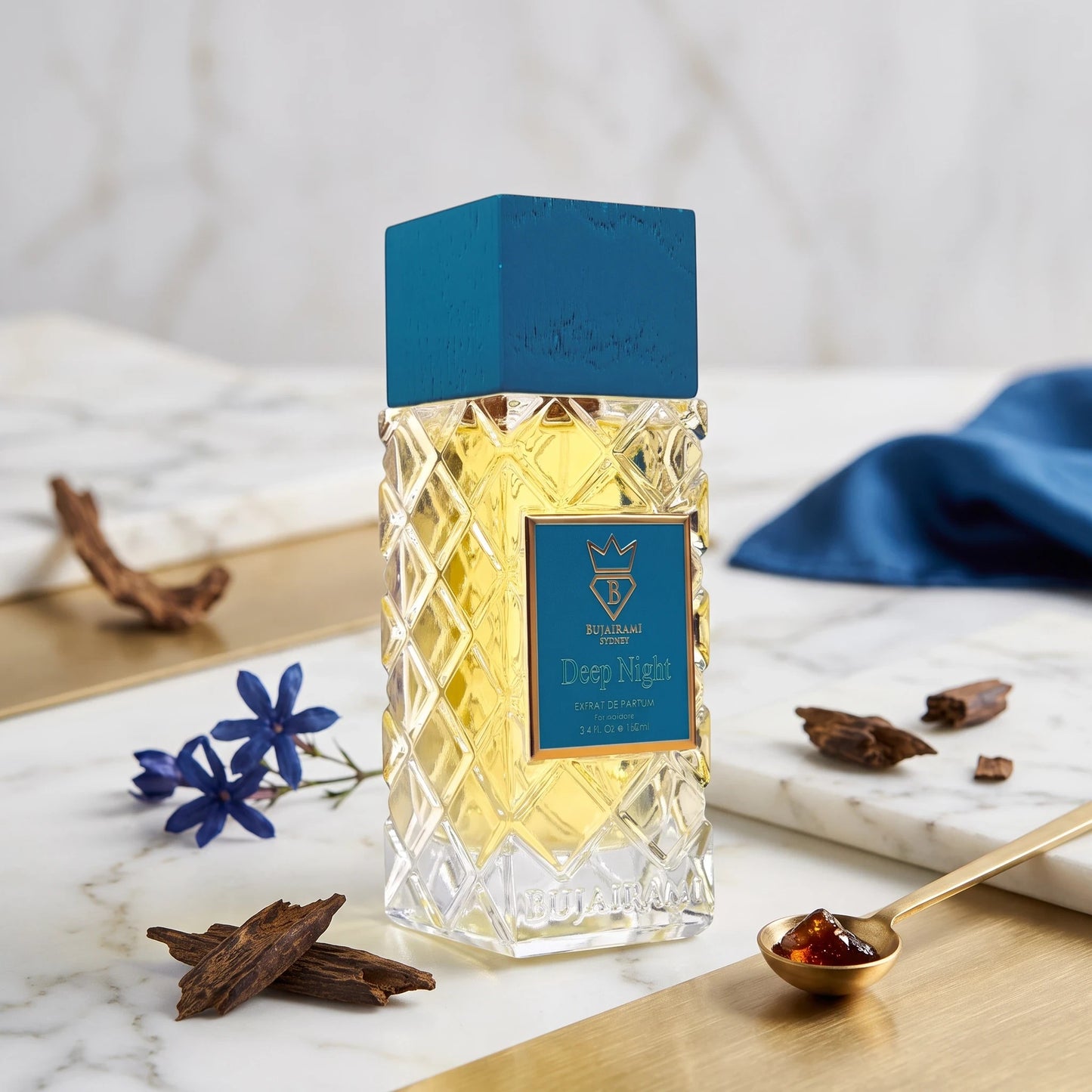 Soghaat Bujairami Deep Night 100ml Extrait de Parfum in a faceted glass bottle with a blue cap on a marble surface.