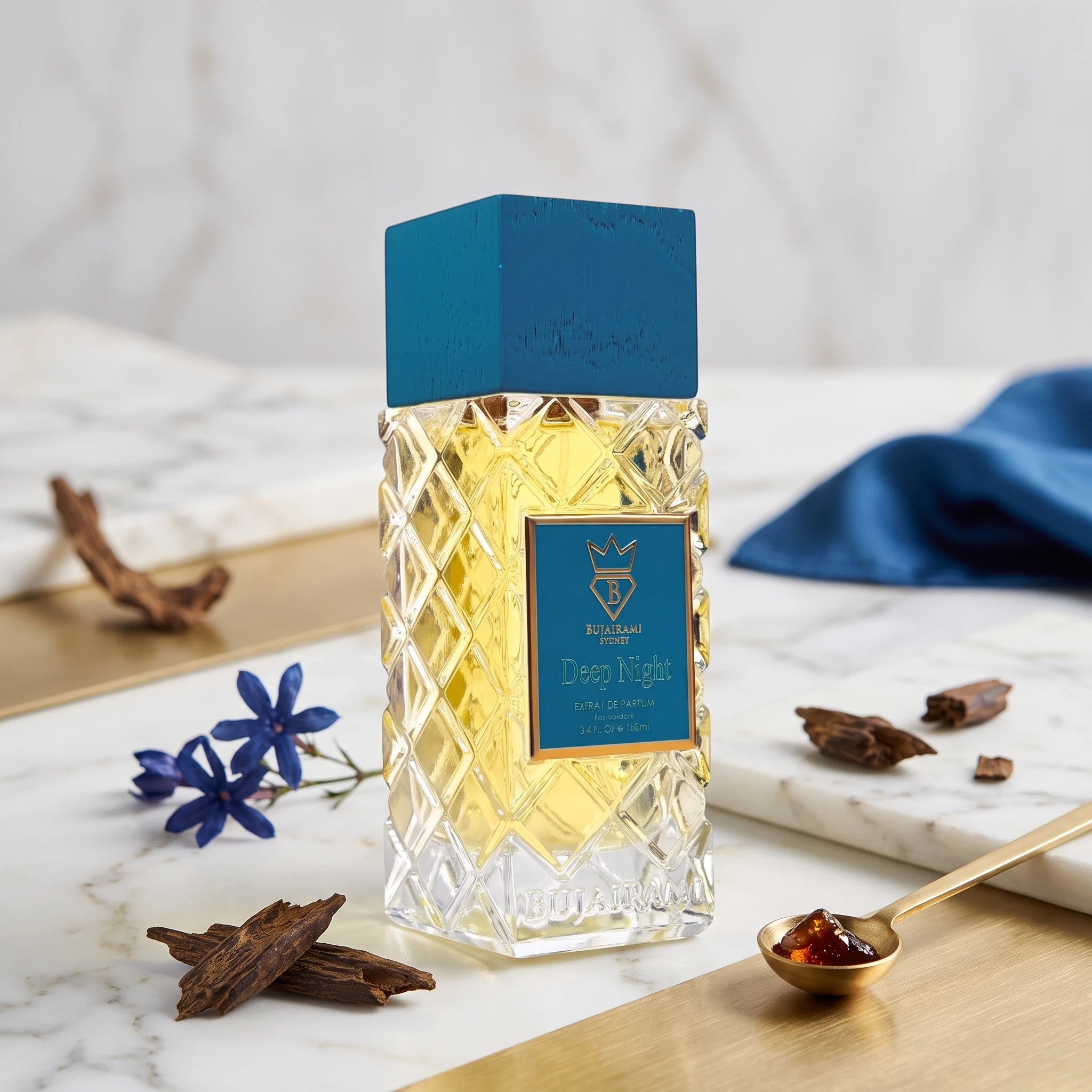 Soghaat Bujairami Deep Night 100ml Extrait de Parfum in a faceted glass bottle with a blue cap on a marble surface.