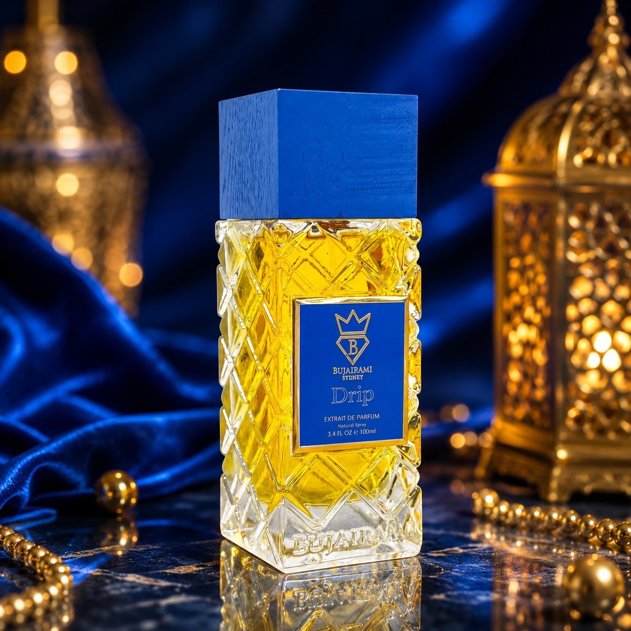 Soghaat Bujairami Drip 100ml Extrait de Parfum in a textured glass bottle with a blue cap on a dark blue silk surface.