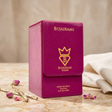 Soghaat Bujairami Imperial Oud Extrait de Parfum in a magenta leather-style box with gold branding on a marble surface.