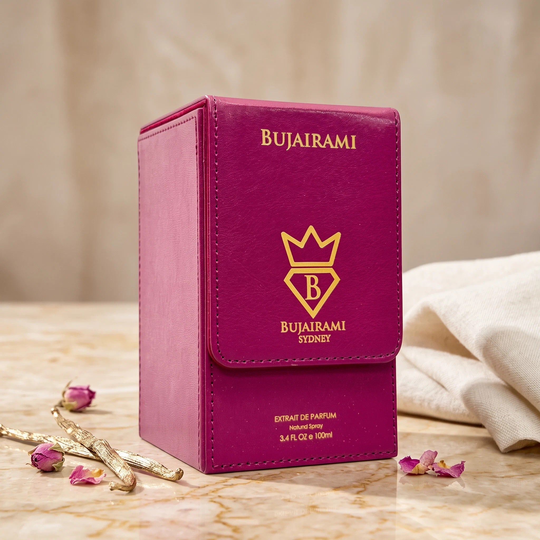 Soghaat Bujairami Imperial Oud Extrait de Parfum in a magenta leather-style box with gold branding on a marble surface.