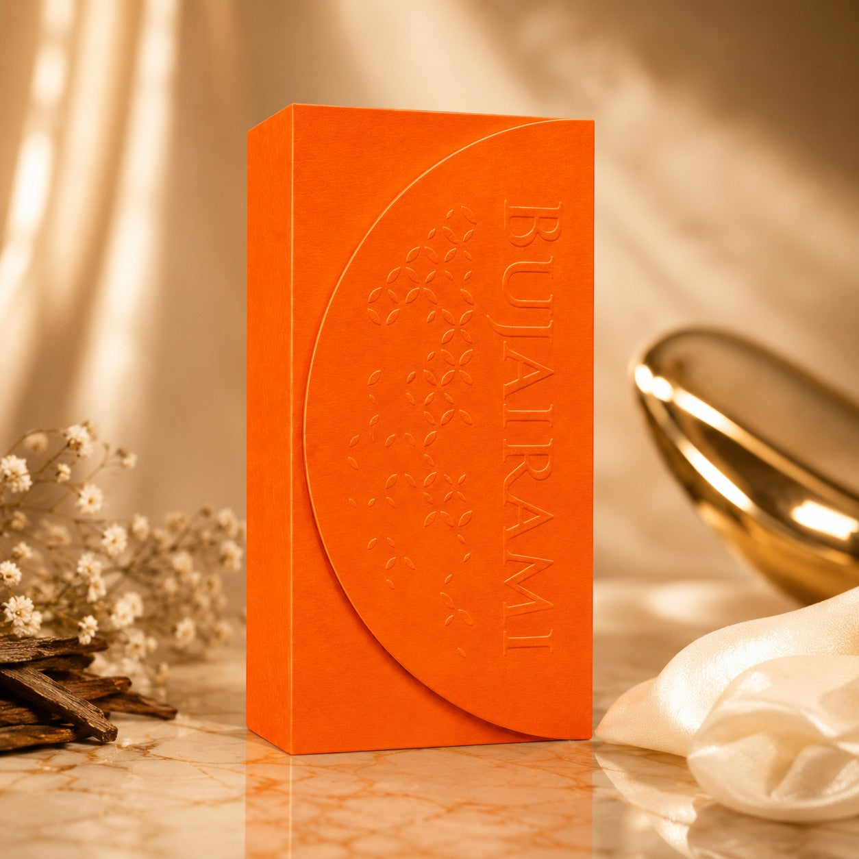 Soghaat Bujairami Legacy 100ml Extrait de Parfum in a vibrant orange box with embossed floral details on a marble surface.