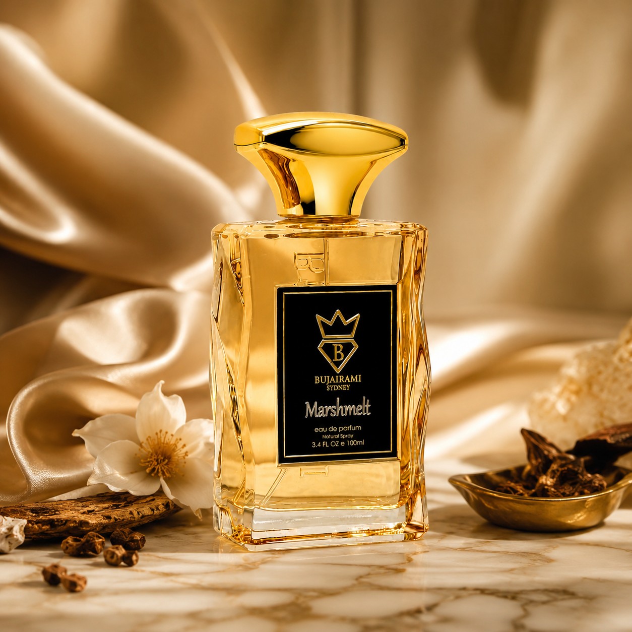Soghaat Bujairami Marshmelt 100ml Eau de Parfum bottle with gold cap on a marble surface with silk fabric background.