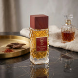 Soghaat Bujairami Oud Money Extrait de Parfum in a textured glass bottle with a dark wood cap on a marble surface.