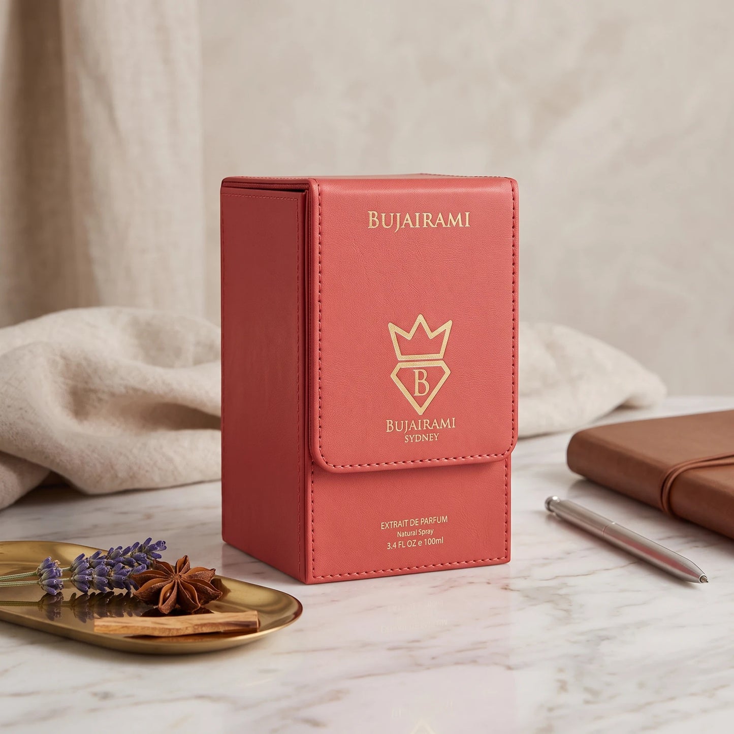 Soghaat Bujairami Powder Affair 100ml Extrait de Parfum in a coral-coloured leather-textured box on a marble surface.