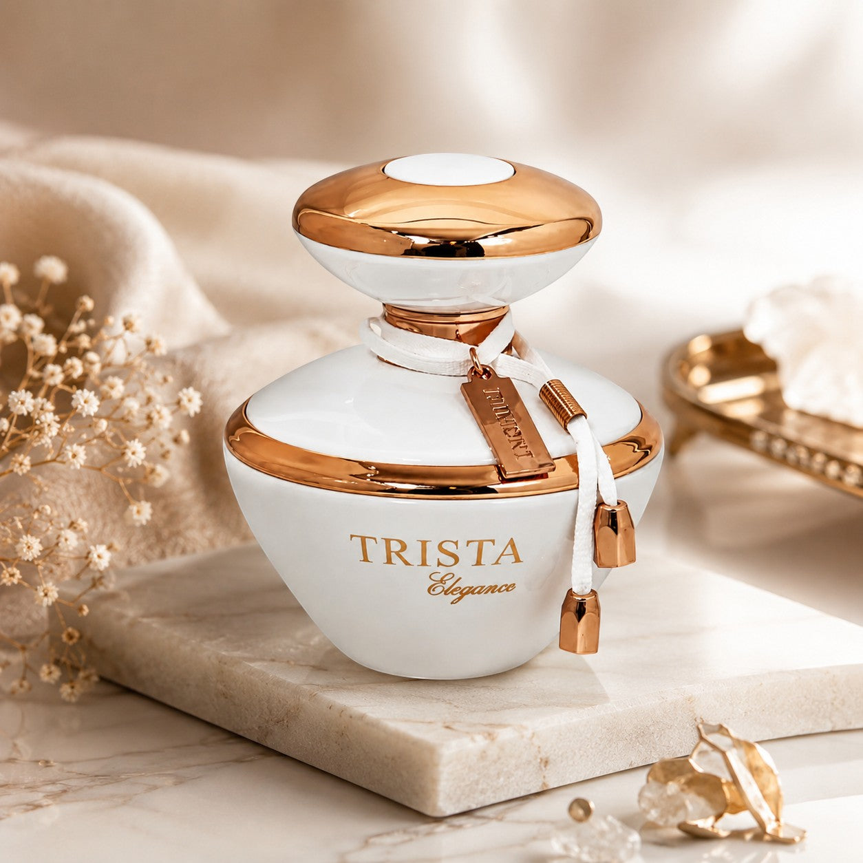 Soghaat Dumont Paris Trista Elegance Eau de Parfum in a white and gold bottle with a decorative charm on a marble stand.