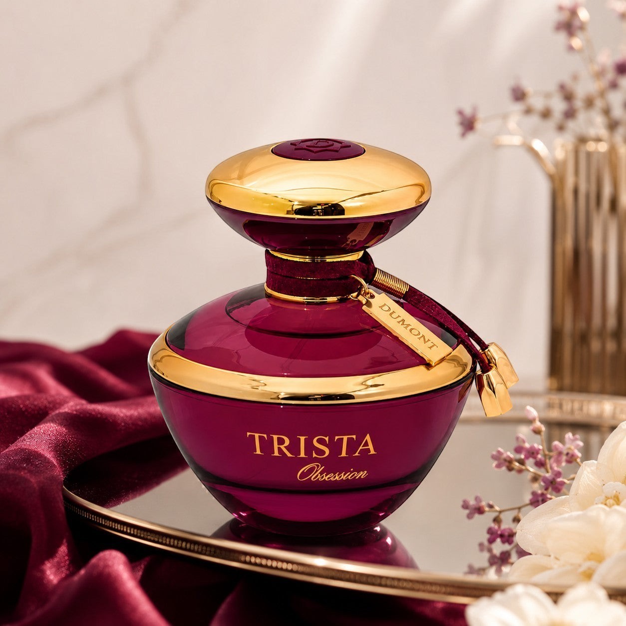 Soghaat Dumont Paris Trista Obsession Eau de Parfum in a deep purple glass bottle with gold accents on a silk cloth.