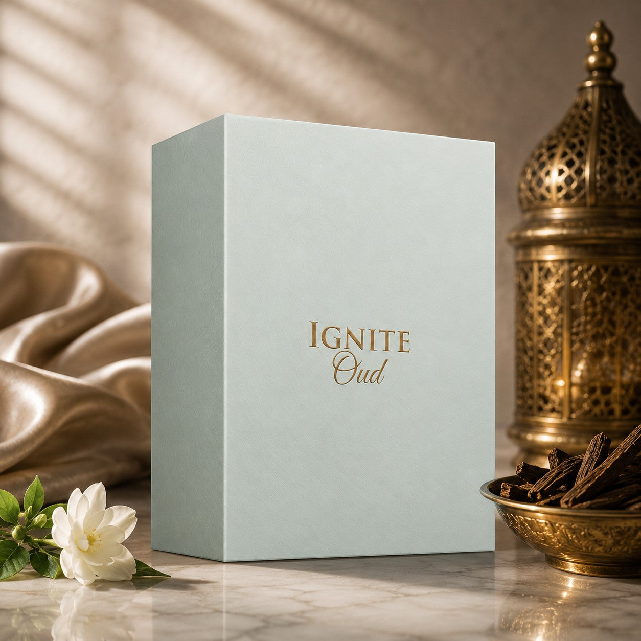 Soghaat Ignite Oud 60ml Eau de Parfum box with gold lettering, styled with a white flower and oud wood chips.