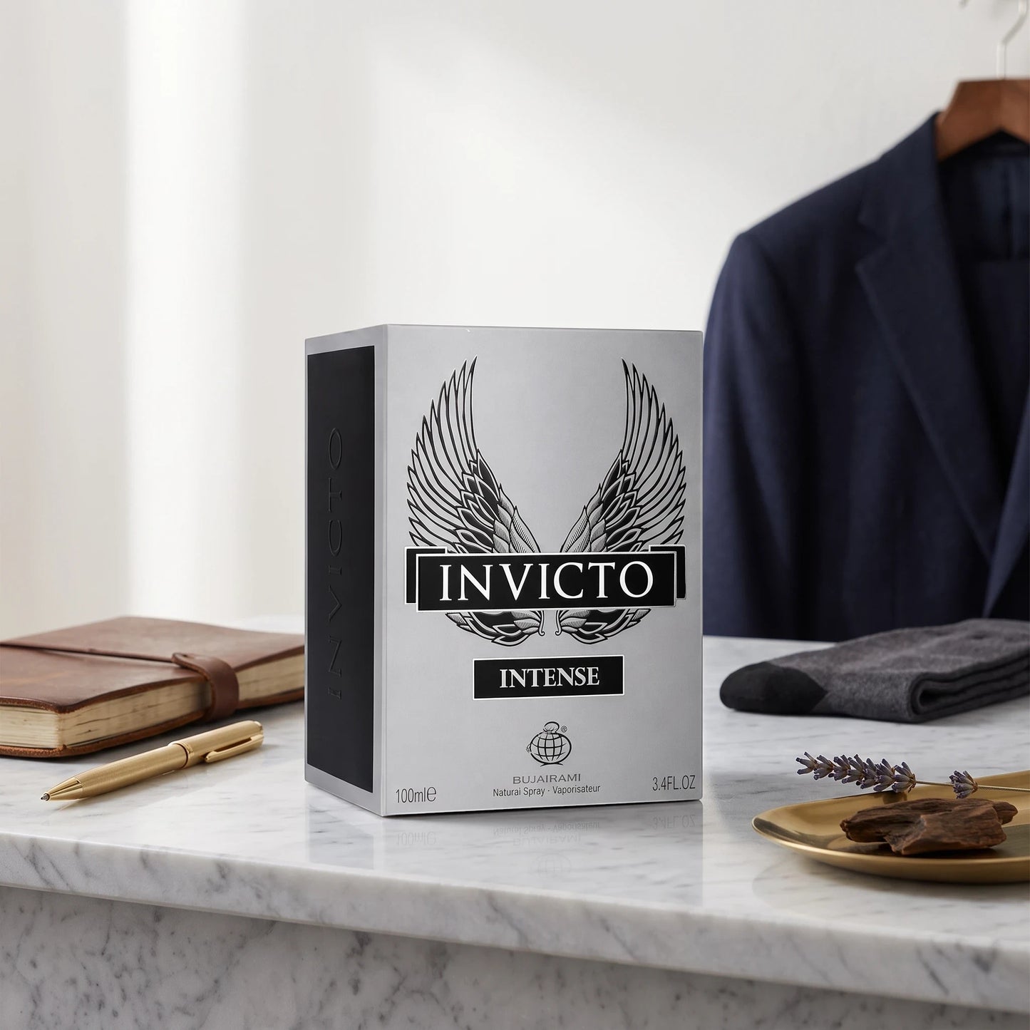 Soghaat Invicto Intense 100ml Eau de Parfum box featuring wing graphics on a marble desk with a suit jacket background