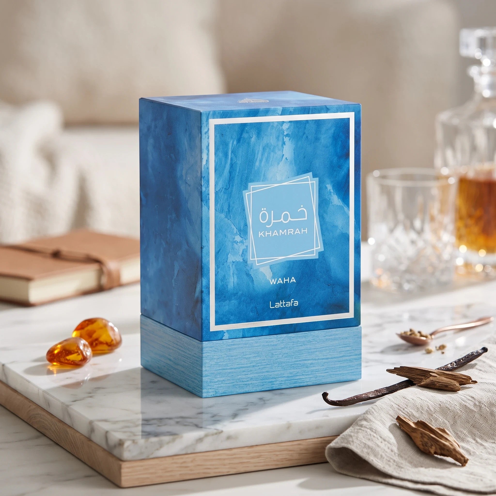 Soghaat Lattafa Khamrah Waha unisex Eau de Parfum bottle in a blue textured box on a marble surface with vanilla beans.