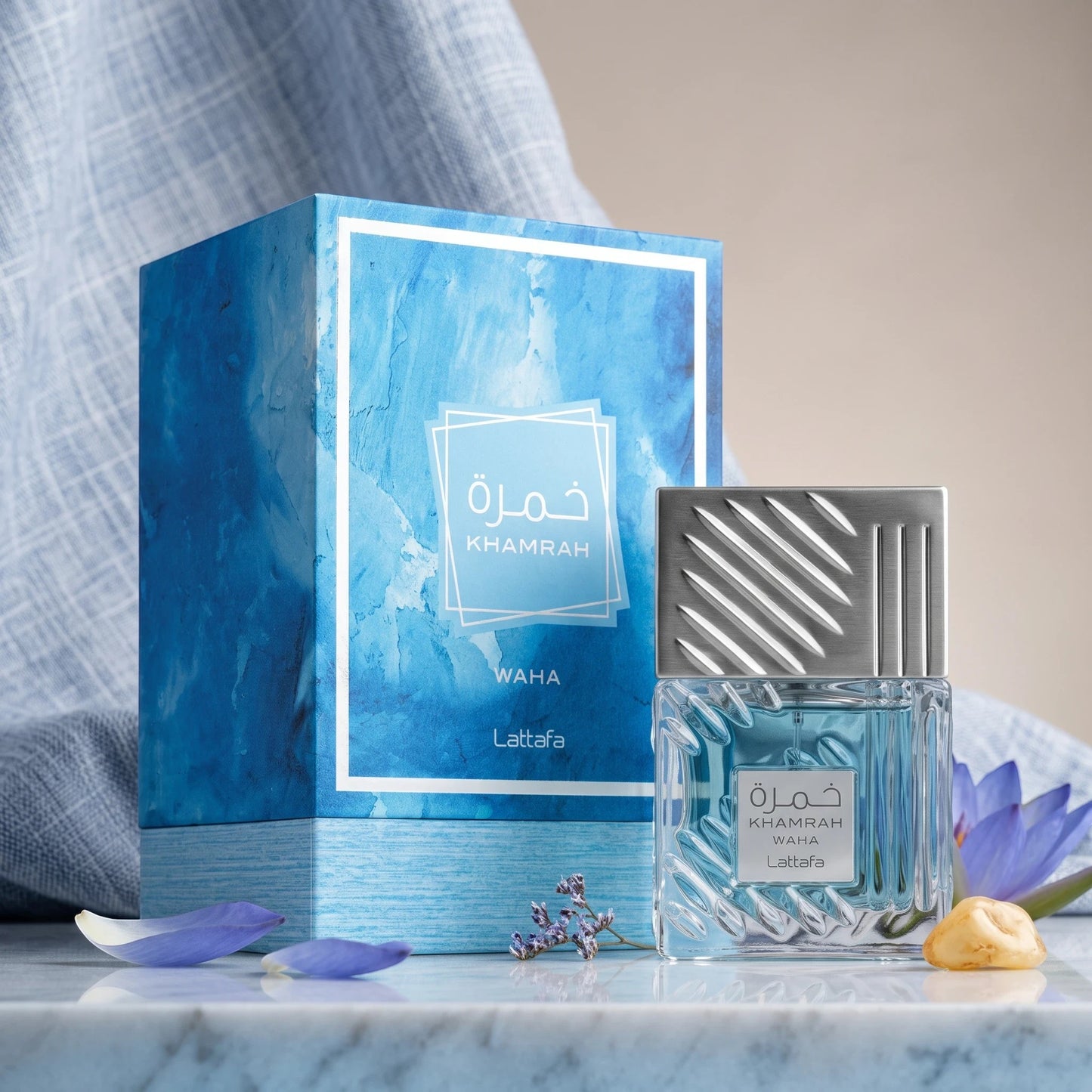 Soghaat Lattafa Khamrah Waha unisex Eau de Parfum bottle and blue textured box on a marble surface with floral accents.