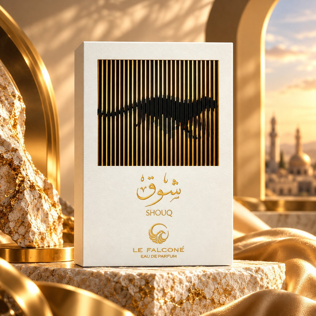 Soghaat Le Falcone Shouq eau de parfum bottle in a white box with gold accents, set on stone against a sunset backdrop.