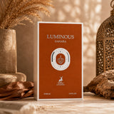 Soghaat Luminous Sahara Eau de Parfum by Maison Alhambra in a rust-orange box, set against a warm, rustic desert backdrop.