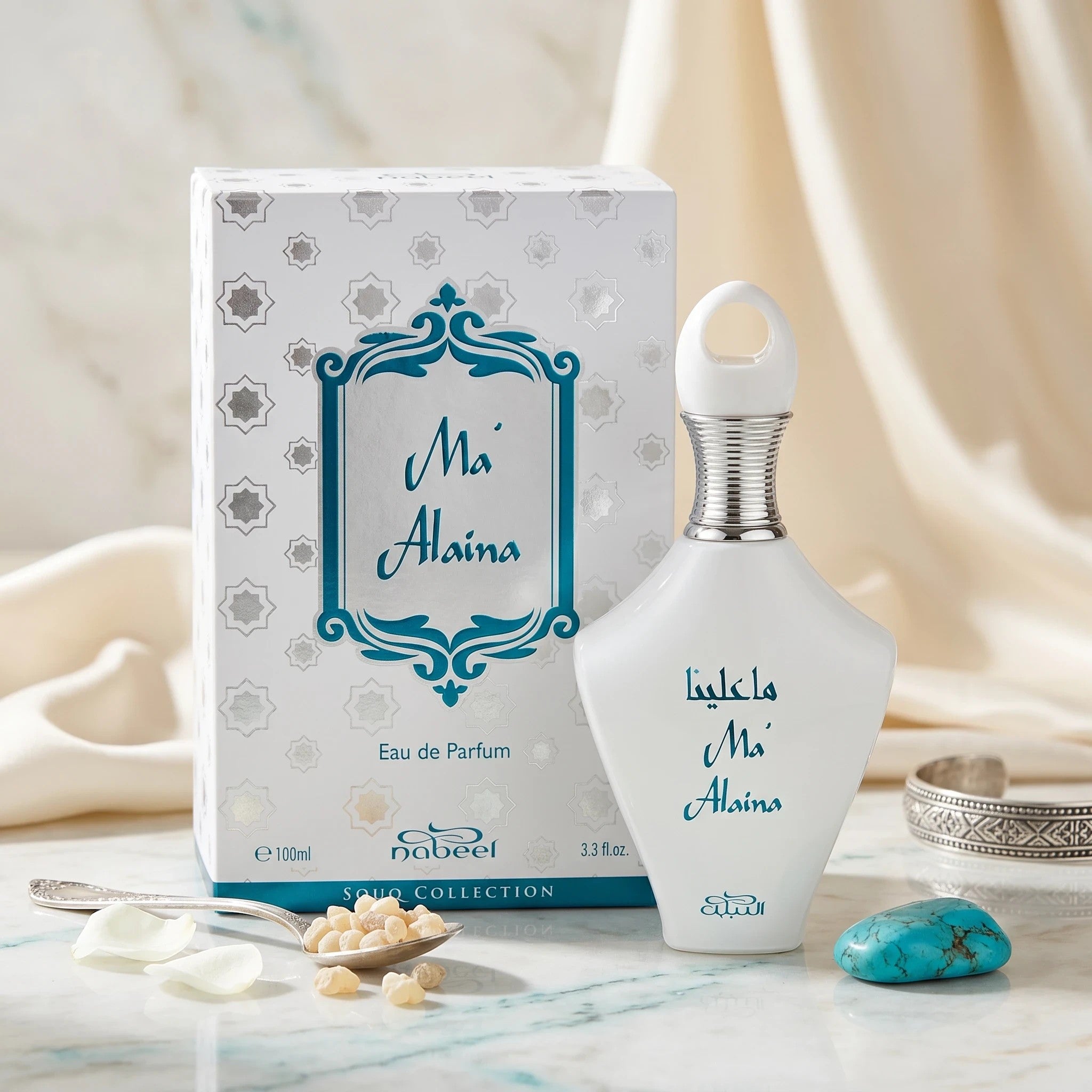 Soghaat Ma'Alaina Eau de Parfum by Nabeel in a white bottle with teal text, displayed with its matching box.