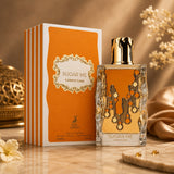 Soghaat Maison Alhambra Sugar Me Carrot Cake Eau de Parfum bottle and orange striped box on a marble surface.