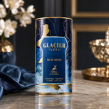 Soghaat Maison Alhambra Glacier Flora Eau de Parfum in a decorative blue and gold cylindrical bottle on a marble table.