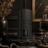 Soghaat Lattafa Musamam Black Intense Eau de Parfum in a cylindrical black snakeskin-textured bottle on marble.