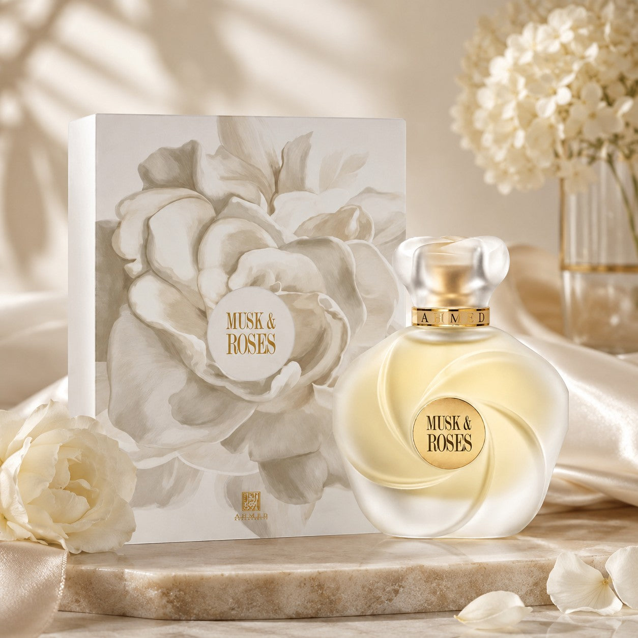 Soghaat Ahmed Al Maghribi Musk & Roses Extrait de Parfum bottle and floral gift box on a marble surface with white roses.