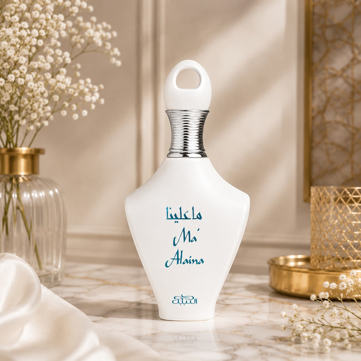 Soghaat Nabeel Ma'Alaina Eau de Parfum in a white bottle with blue text, displayed on a marble surface with flowers.