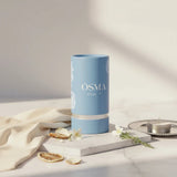 Soghaat Osma Citrus' F Eau de Parfum in a light blue cylindrical bottle with white floral accents. Notes of citrus, rose, and musk.