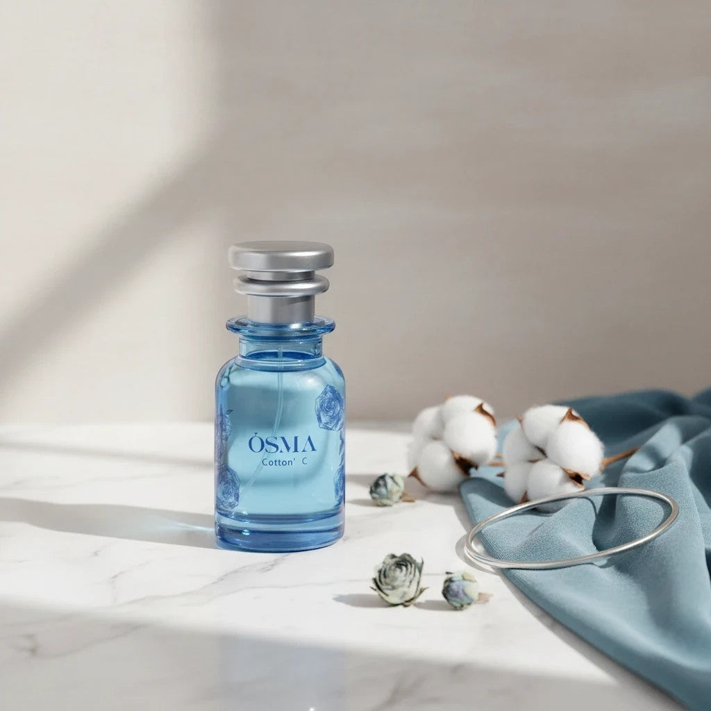 Soghaat Osma Cotton' C Eau de Parfum in a blue glass bottle with a silver cap, featuring floral motifs. Accented by cotton bolls and a silver bracelet.