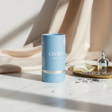 Soghaat Osma Floral R Eau de Parfum in a light blue cylindrical case with floral accents. A small silver perfume bottle sits on a gold tray with lavender.