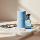 Soghaat Osma Paudree F Eau de Parfum bottle and blue cylindrical box with floral design. Includes lavender sprigs and rose petals.