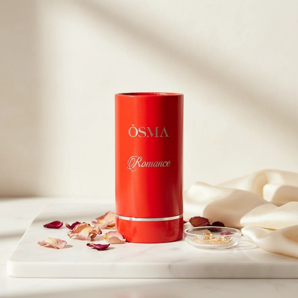 Soghaat Osma Romance Eau de Parfum in a red cylindrical bottle with silver lettering, surrounded by rose petals.
