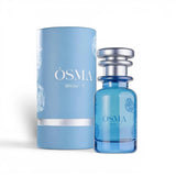Soghaat Osma White F Eau de Parfum bottle and cylindrical box, both light blue with white floral accents. Sweet gourmand fragrance.