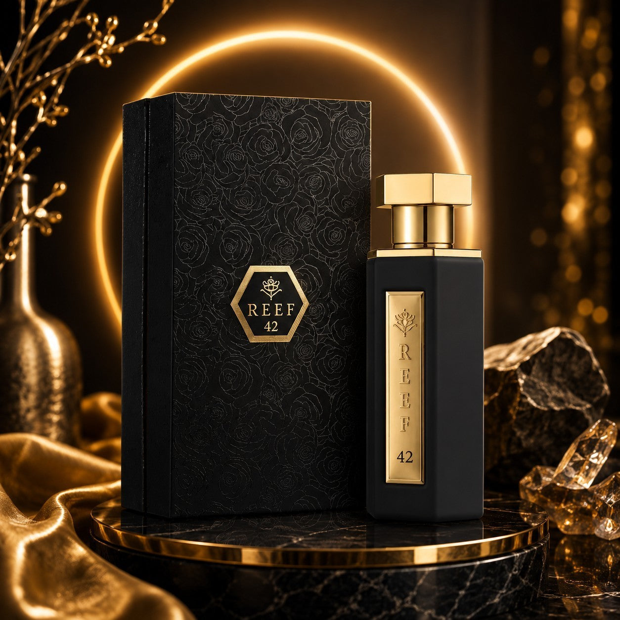 Soghaat Reef 42 unisex Eau de Parfum bottle and black embossed box with gold accents on a marble pedestal.