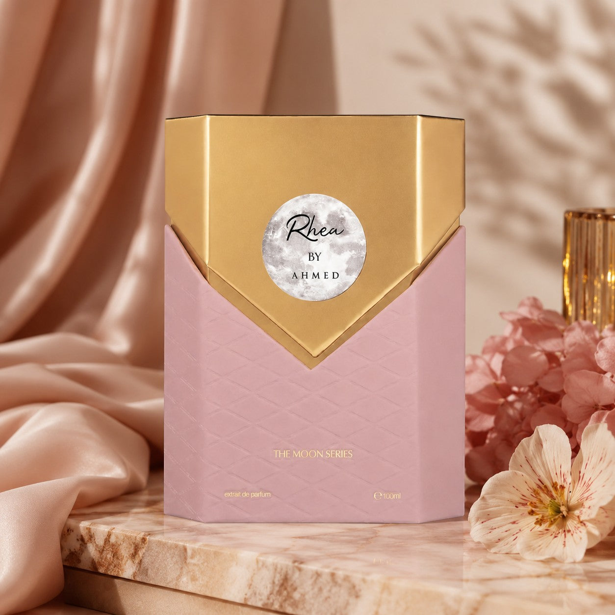 Soghaat Rhea 100ml Extrait de Parfum in a pink and gold hexagonal bottle, displayed on a marble surface with flowers.