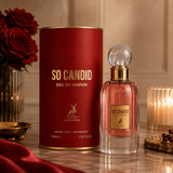 Soghaat Maison Alhambra So Candid 85ml Eau de Parfum bottle and red cylindrical box with gold lettering on a table.
