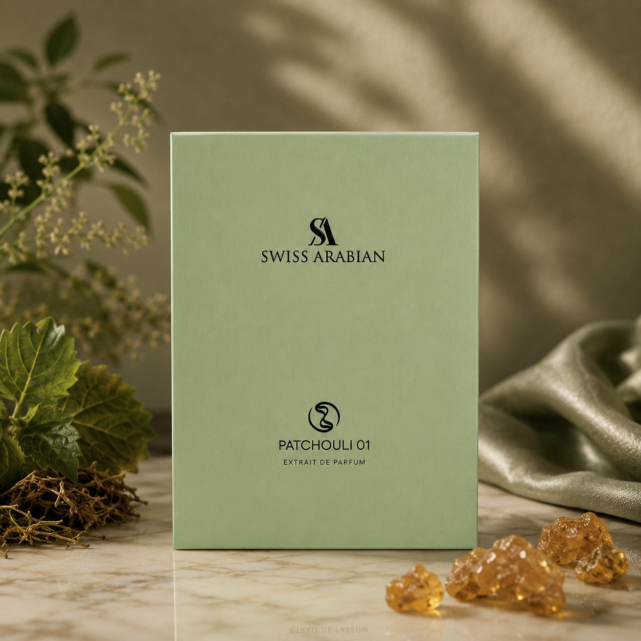 Soghaat Swiss Arabian Patchouli 01 Extrait de Parfum box in sage green, displayed with patchouli leaves and resin.