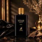 Soghaat Maison Alhambra Your Touch Oud Eau de Parfum in a black bottle with gold accents, set with oud wood pieces.