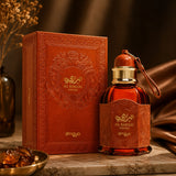 Soghaat Zimaya AL Barari Shore Eau de Parfum bottle and ornate orange box on a marble surface with warm lighting.